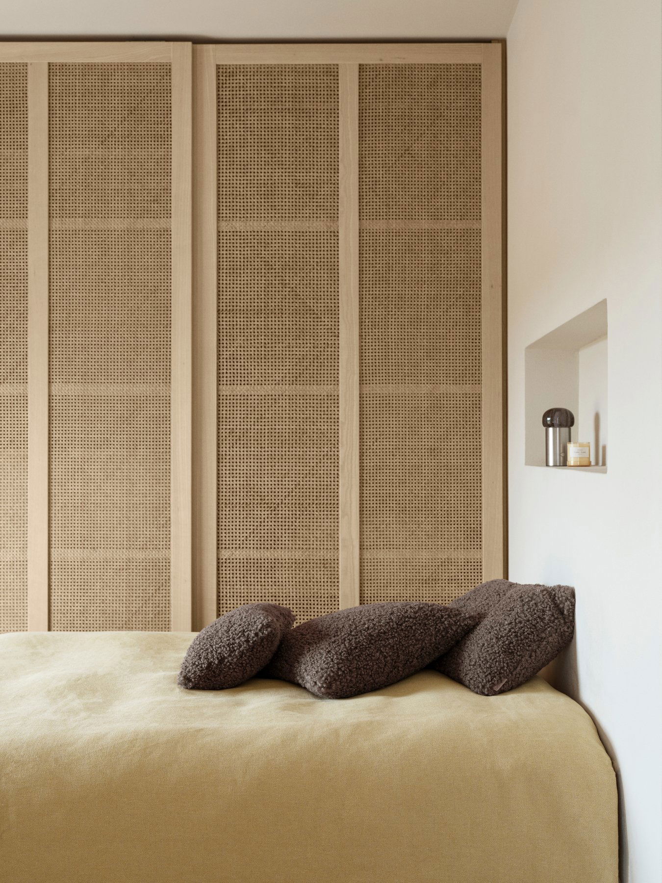 Gemütliches Schlafzimmer mit strukturierten Wänden, weichen Kissen und minimalistischen Dekorelementen.