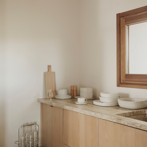 Minimalist kitchen countertop with white dishes and wooden accents.