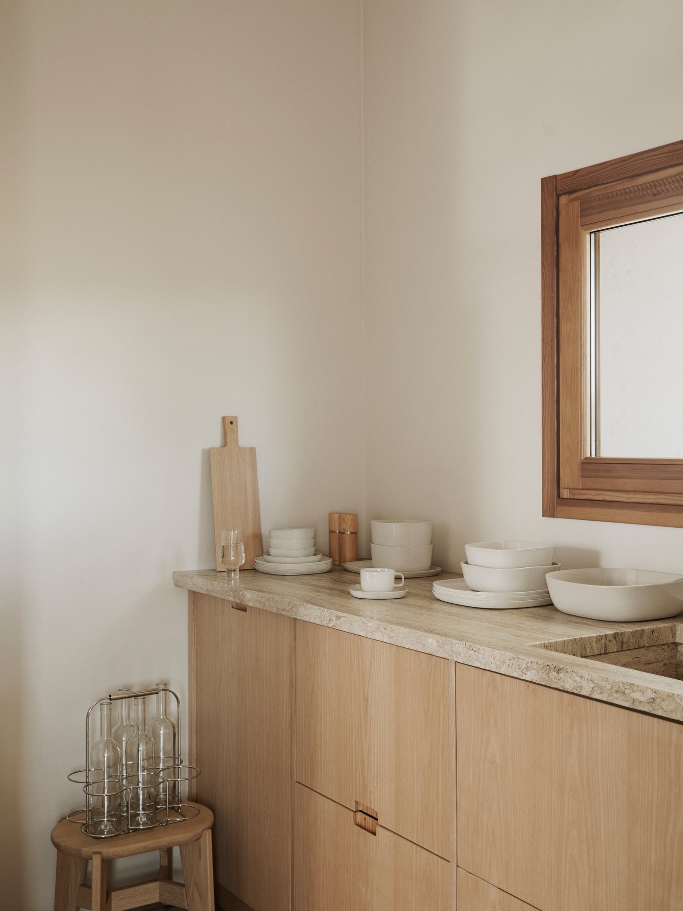 Minimalist kitchen countertop with white dishes and wooden accents.