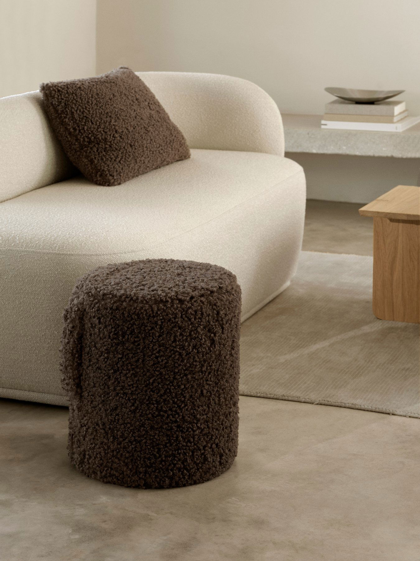 Gemütliche Wohnzimmer-Szene mit einem strukturierten braunen Hocker und einem weichen beigen Sofa.