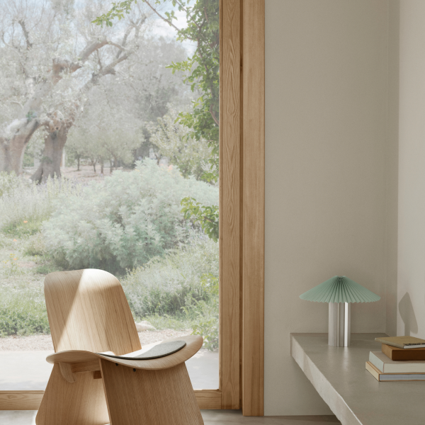 Moderne Holzstuhl neben einer minimalistischen Lampe mit einer ruhigen Aussicht ins Freie.
