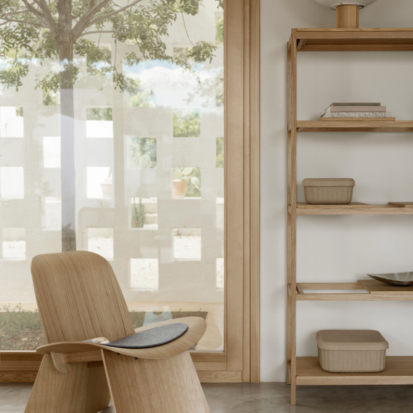 Gemütliches Interieur mit einem Holzstuhl und einem minimalistischen Regal an einem sonnigen Fenster.