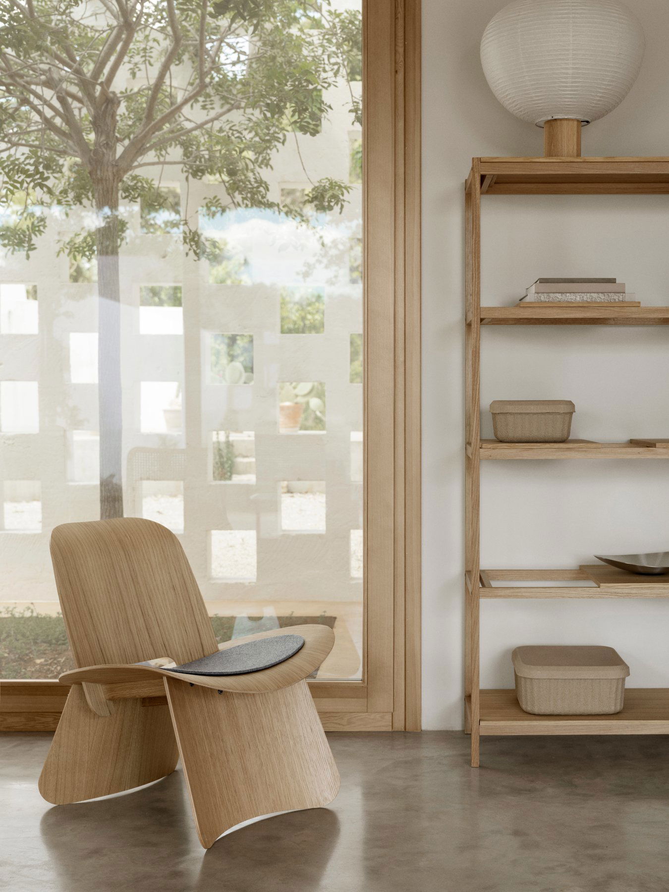 Gemütliches Interieur mit einem Holzstuhl und einem minimalistischen Regal an einem sonnigen Fenster.