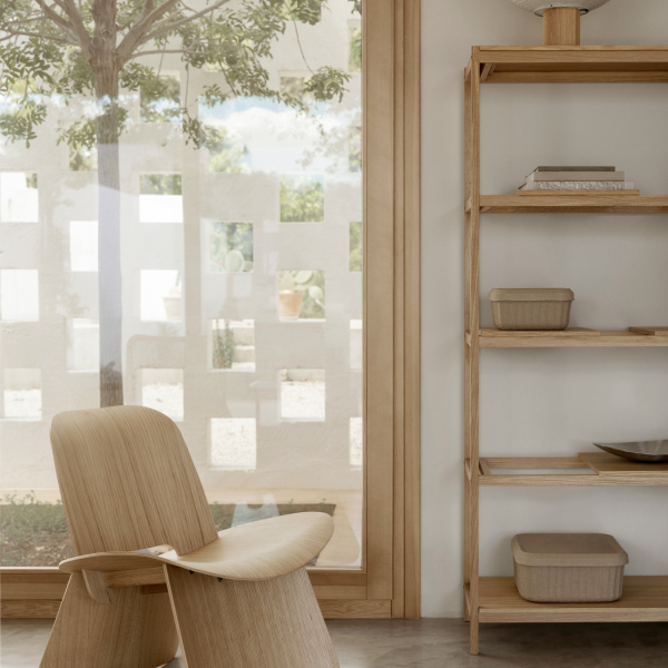 Moderne Holztisch und Regale in einem hellen, minimalistischen Innenraum mit natürlichem Licht.