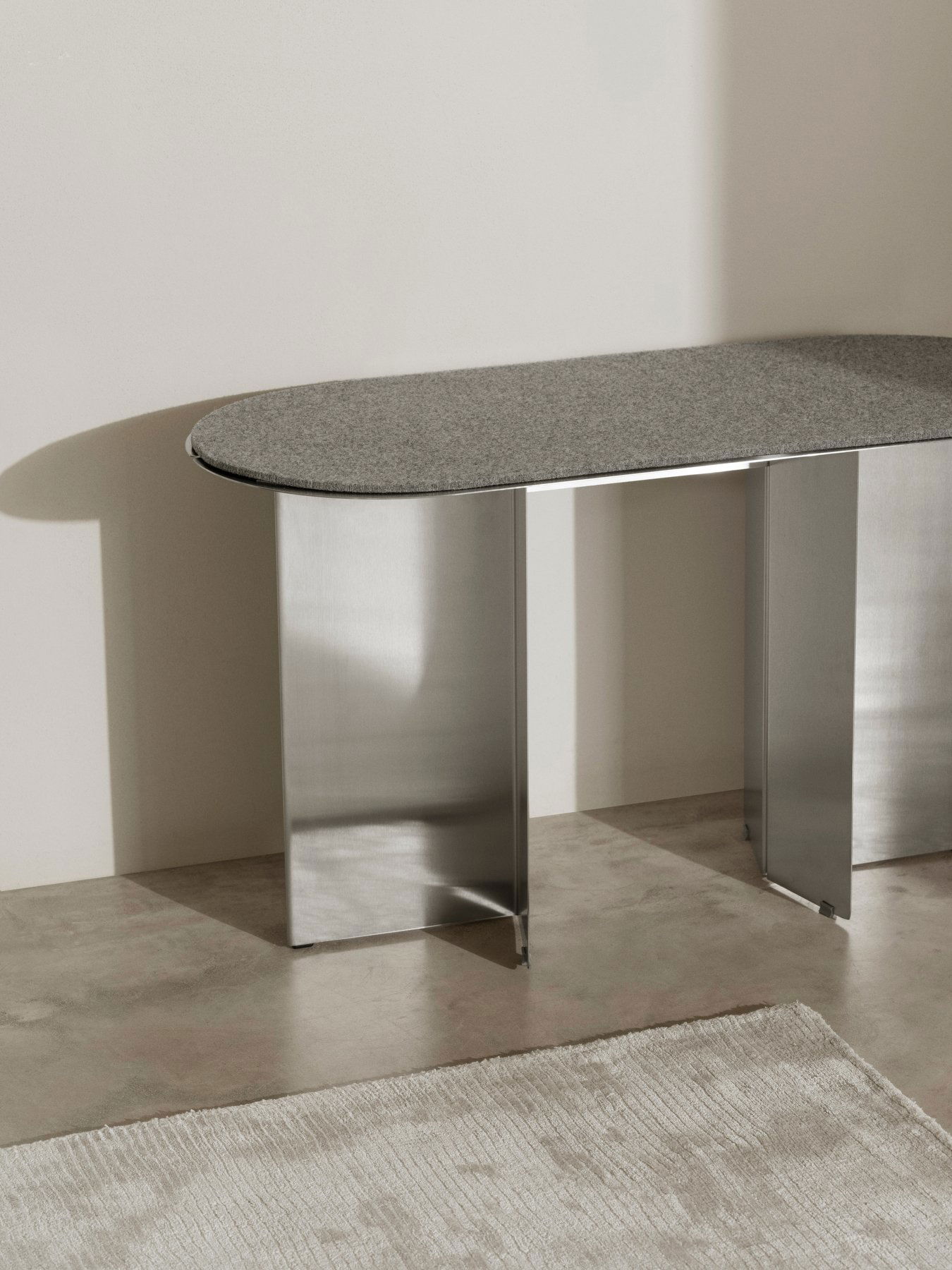 Eleganter moderner Tisch mit einer grauen Steintischplatte und Edelstahlbeinen in einem minimalistischen Ambiente.