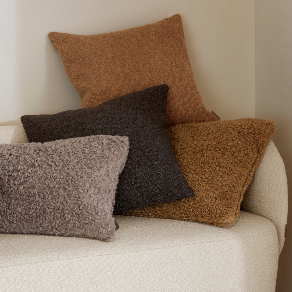Cozy textured pillows in warm tones arranged on a minimalist sofa.