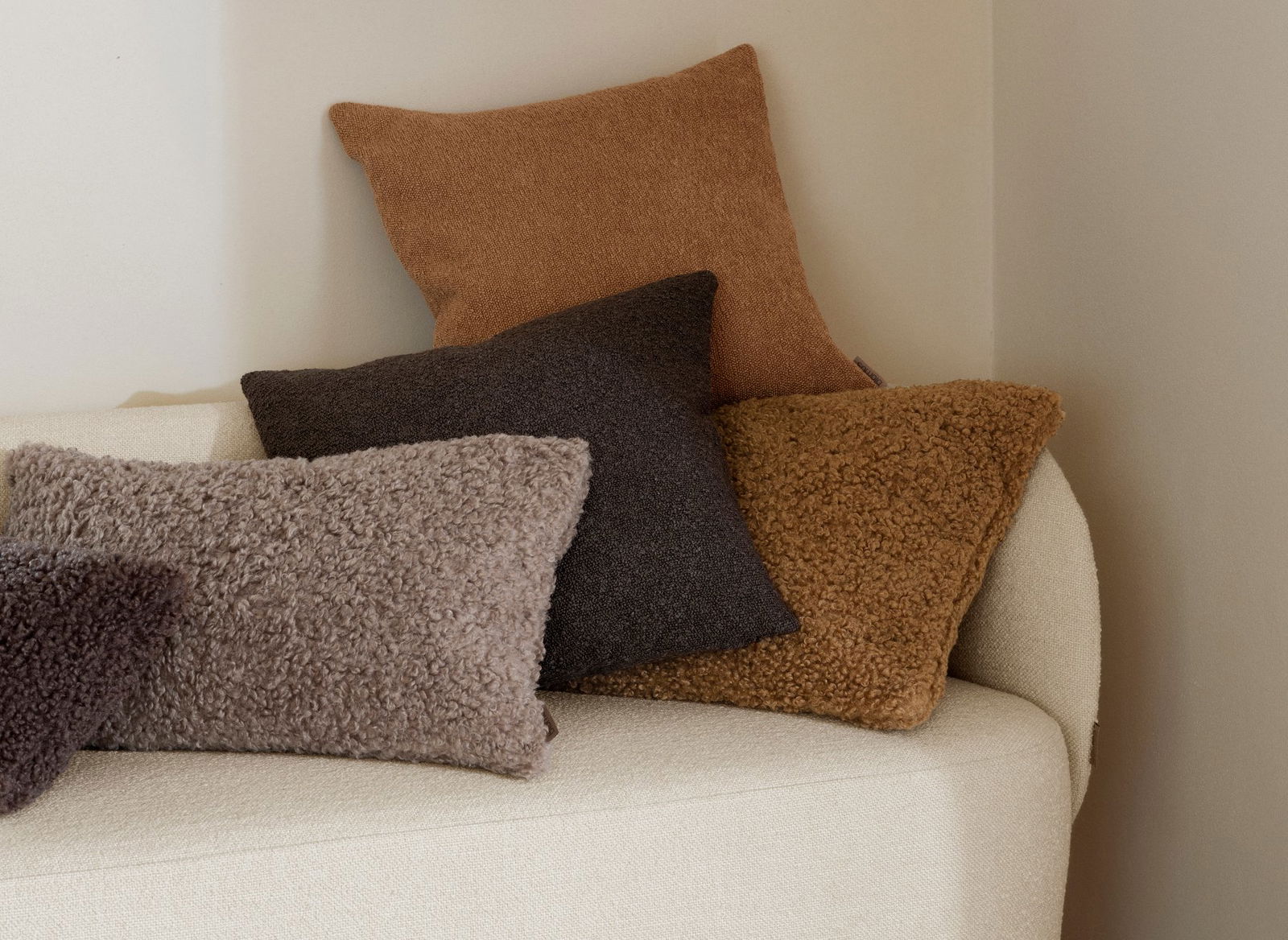 Cozy textured pillows in warm tones arranged on a minimalist sofa.