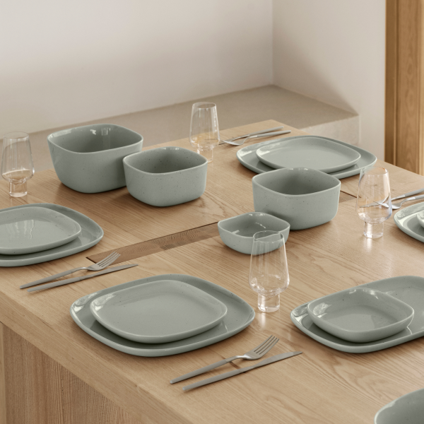 Modernes Esstischset mit hellblauen Keramiktellern und stilvollen Gläsern.