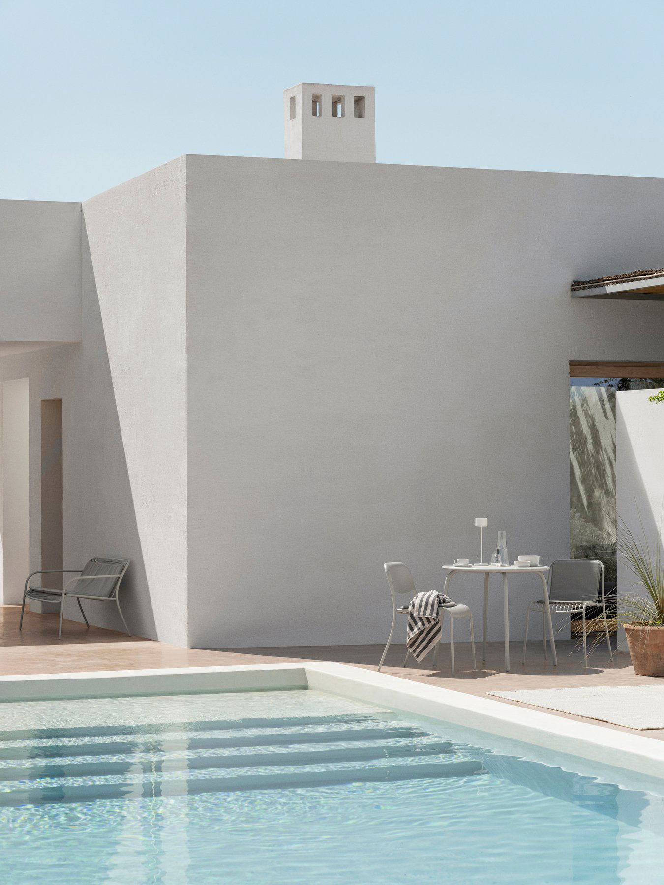 Moderne Außenspeisearea mit minimalistischer Gestaltung neben einem erfrischenden Pool.
