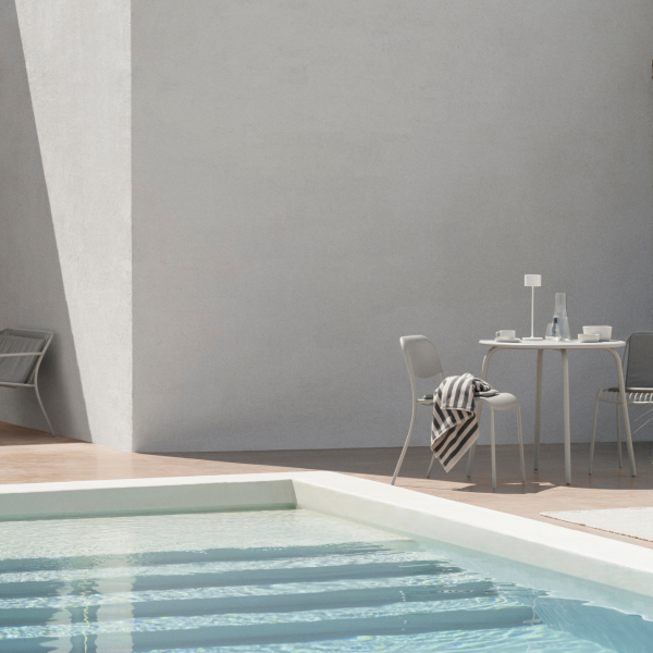 Moderne Außenterrasse mit minimalistischer Dekoration und sanften Schatten an einem ruhigen Pool.