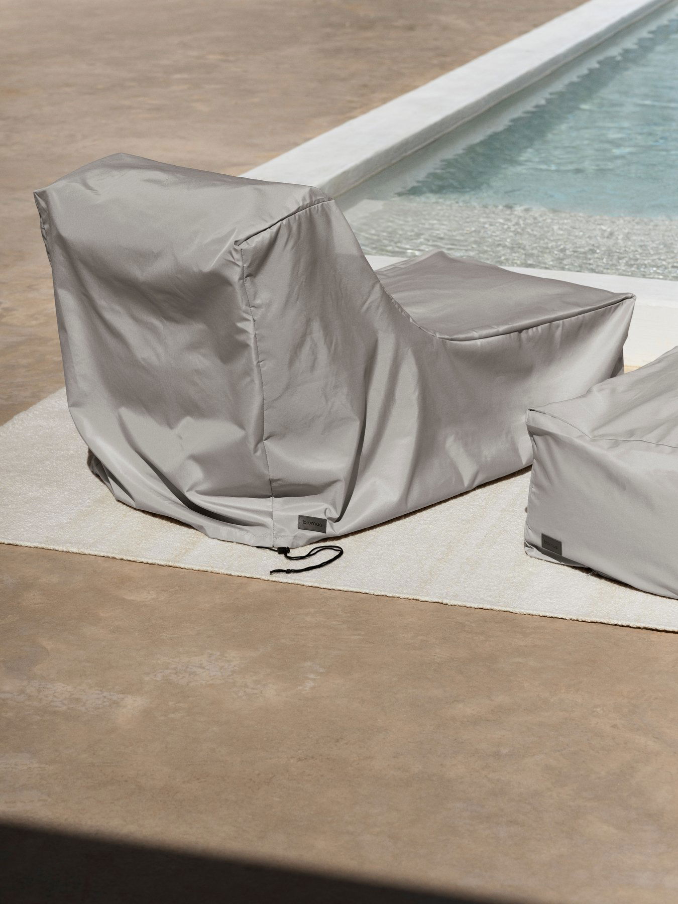 Stylish gray outdoor lounge chairs by a pool for relaxing and enjoying the sun.