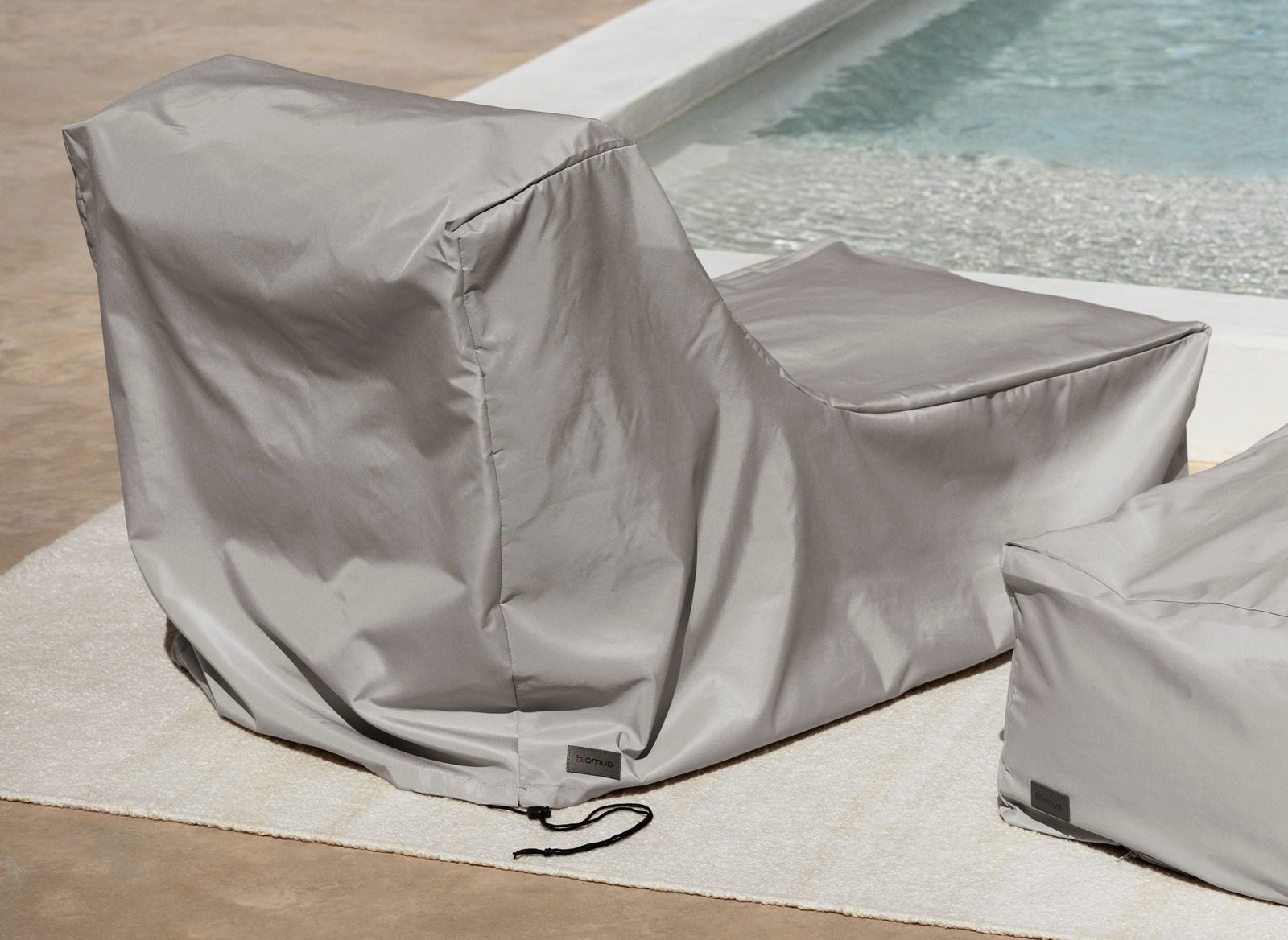 Stylish gray outdoor furniture cover by a swimming pool for weather protection.