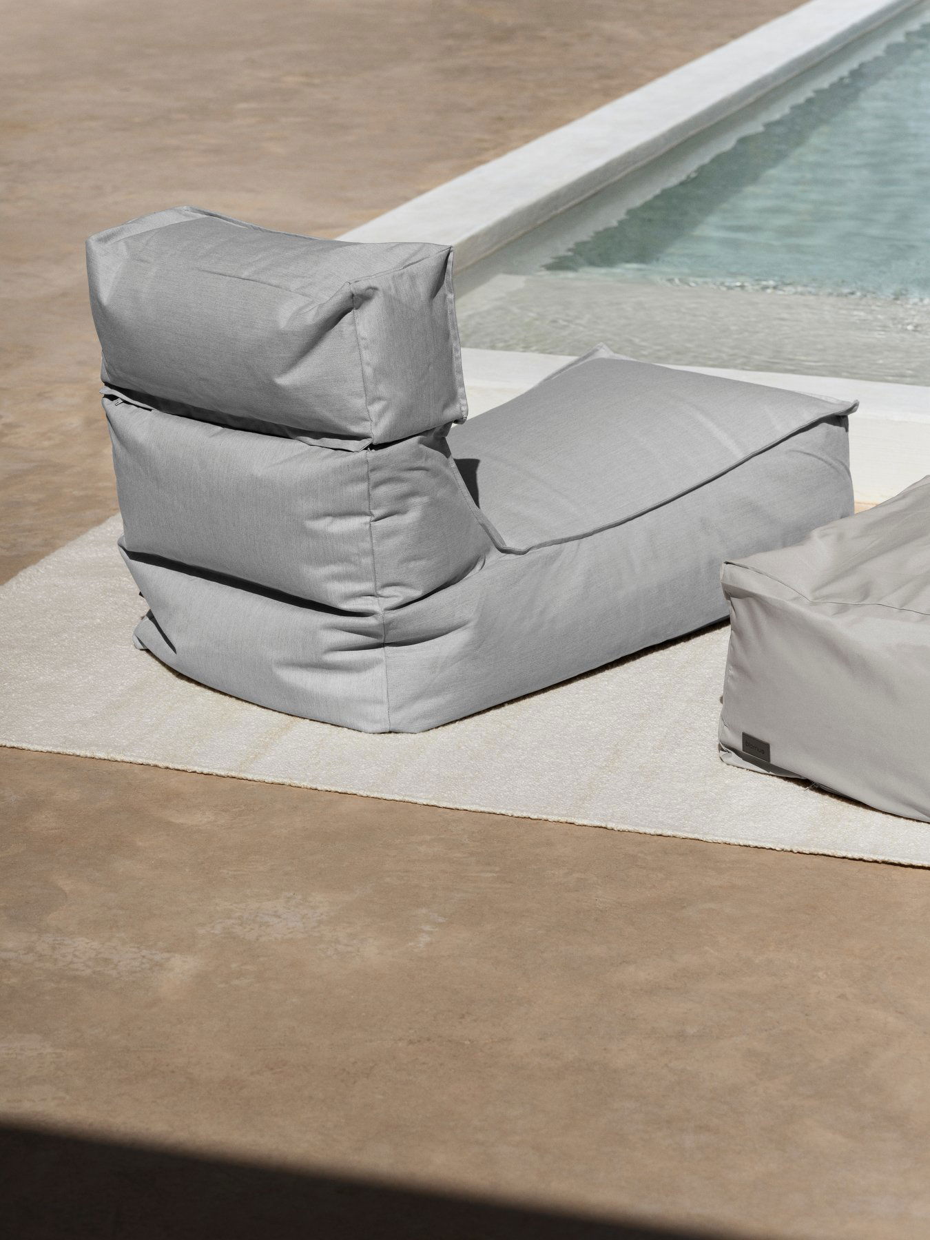 Stylish gray outdoor bean bag chair near a swimming pool.