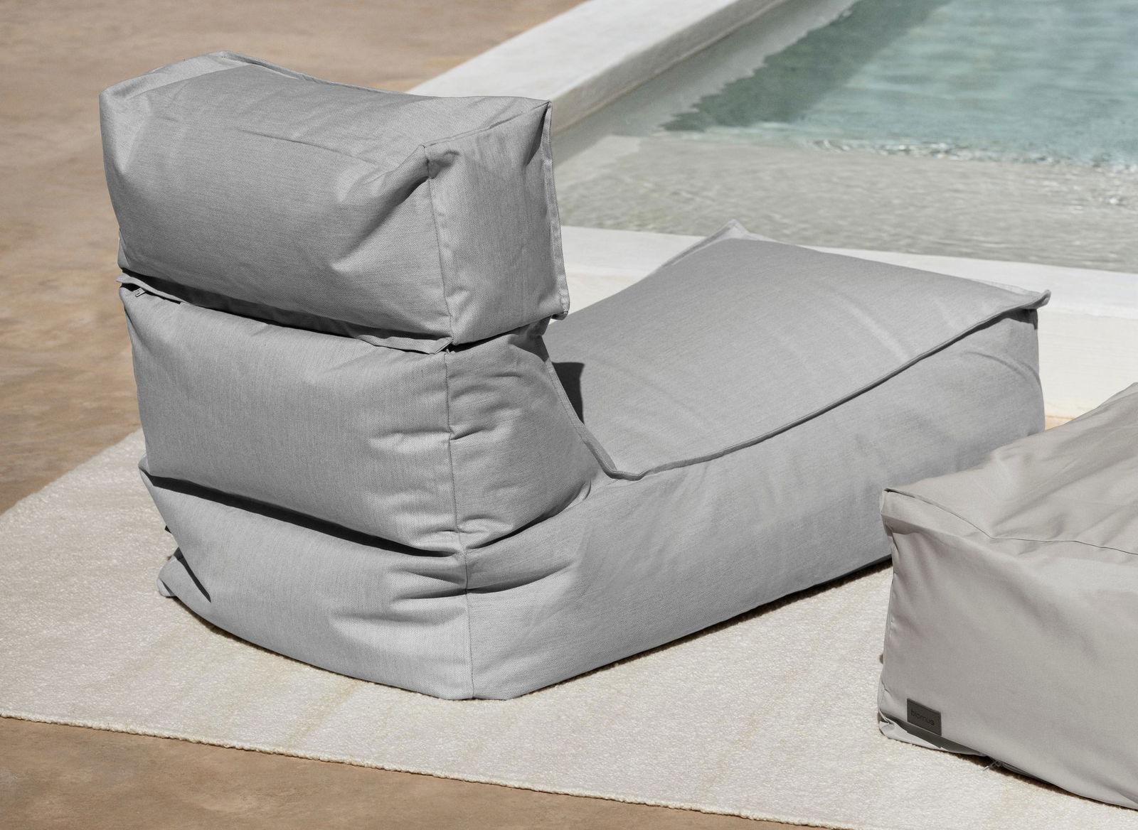 Cozy light gray beanbag chair by a swimming pool on a sunny day.
