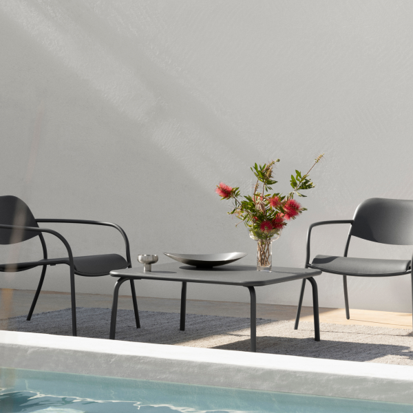 Stylischer Außenbereich mit Sitzgelegenheiten in der Nähe eines Pools, mit einer Vase mit Blumen auf einem Tisch.