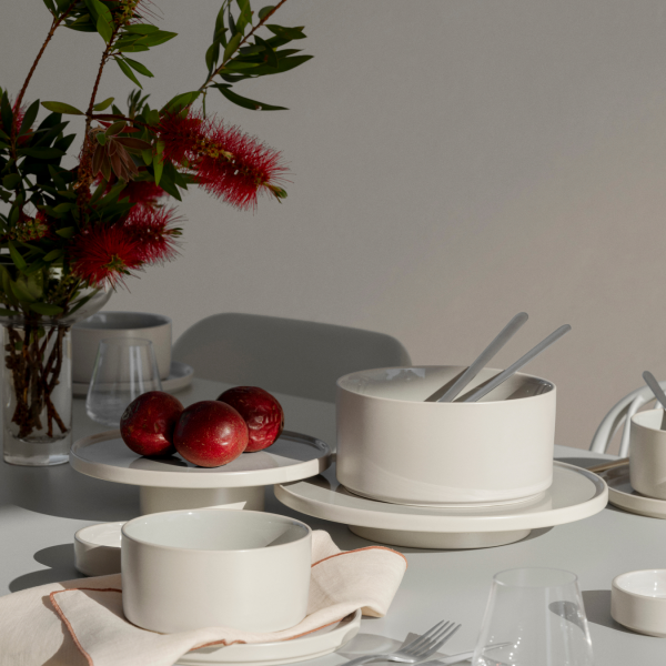 Elegante Tischdekoration mit weißem Geschirr, roten Äpfeln und frischen Blumen.