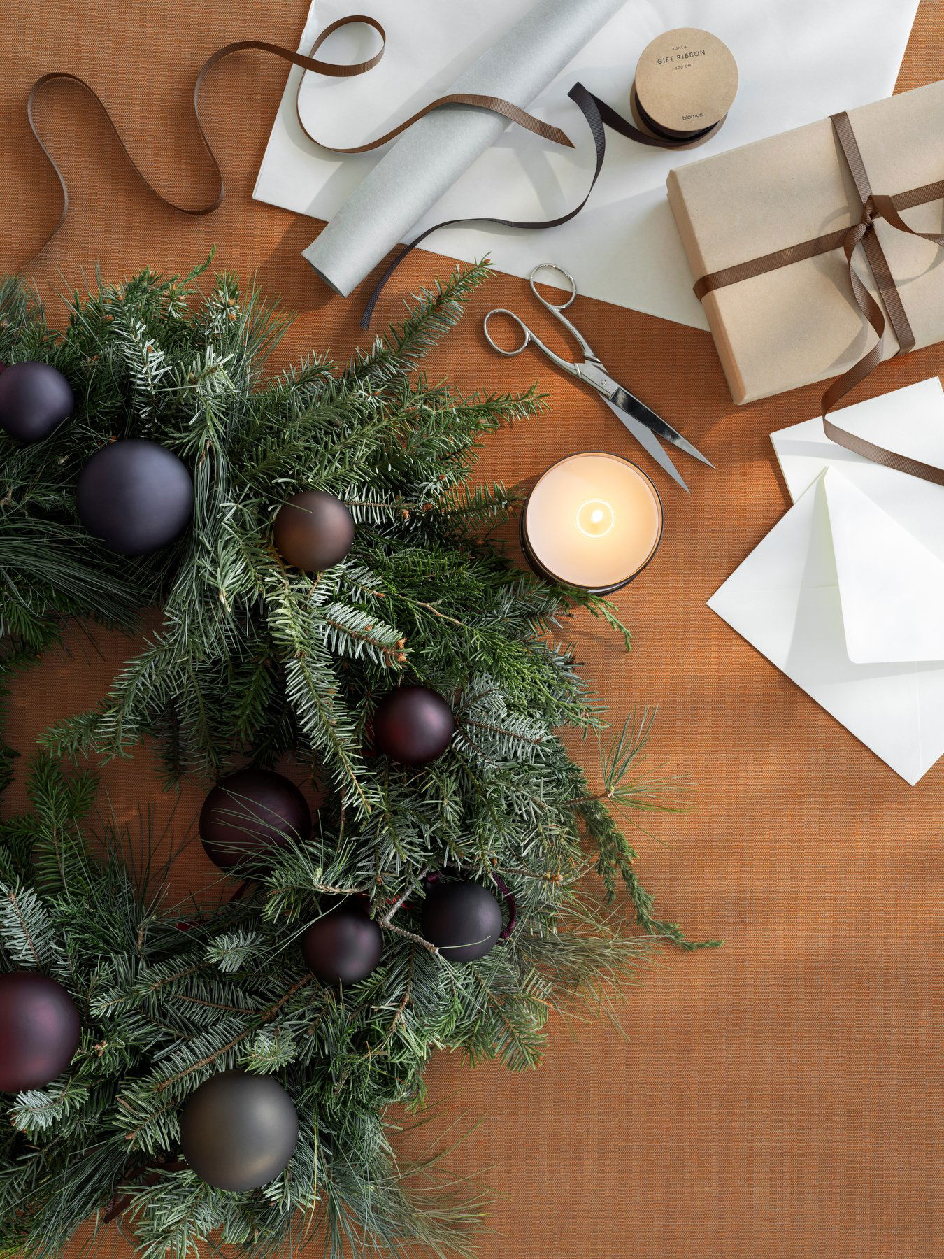Festlicher Weihnachtskranz mit Ornamenten, Kerzen und Geschenken auf einem rustikalen Tisch.