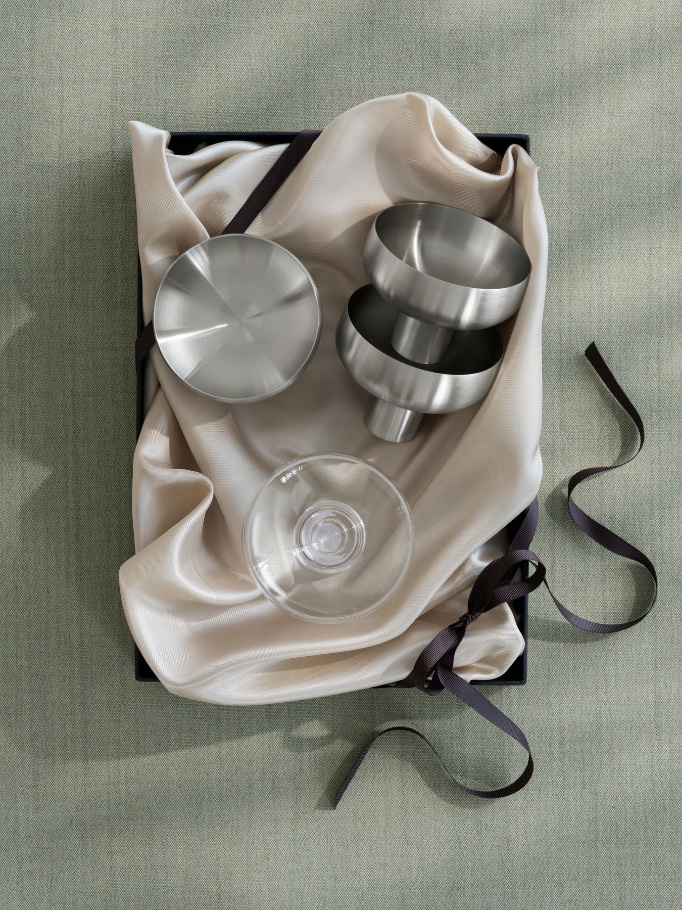 Stilvolle metallische Küchenwerkzeuge schön auf eleganter Stoff in einer Geschenkbox arrangiert.
