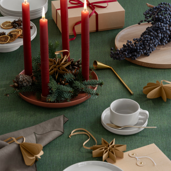 Festive holiday table setting with red candles, pine decor, and elegant tableware.