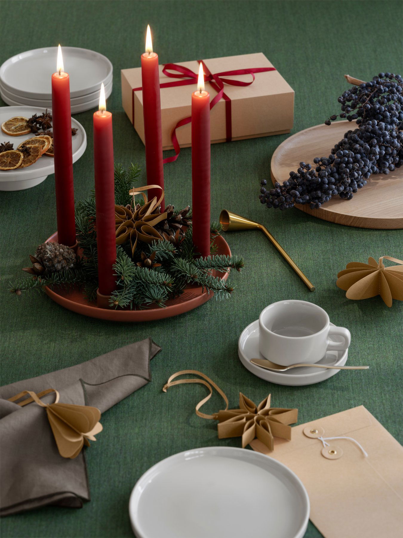 Festive holiday table setting with red candles, pine decor, and elegant tableware.