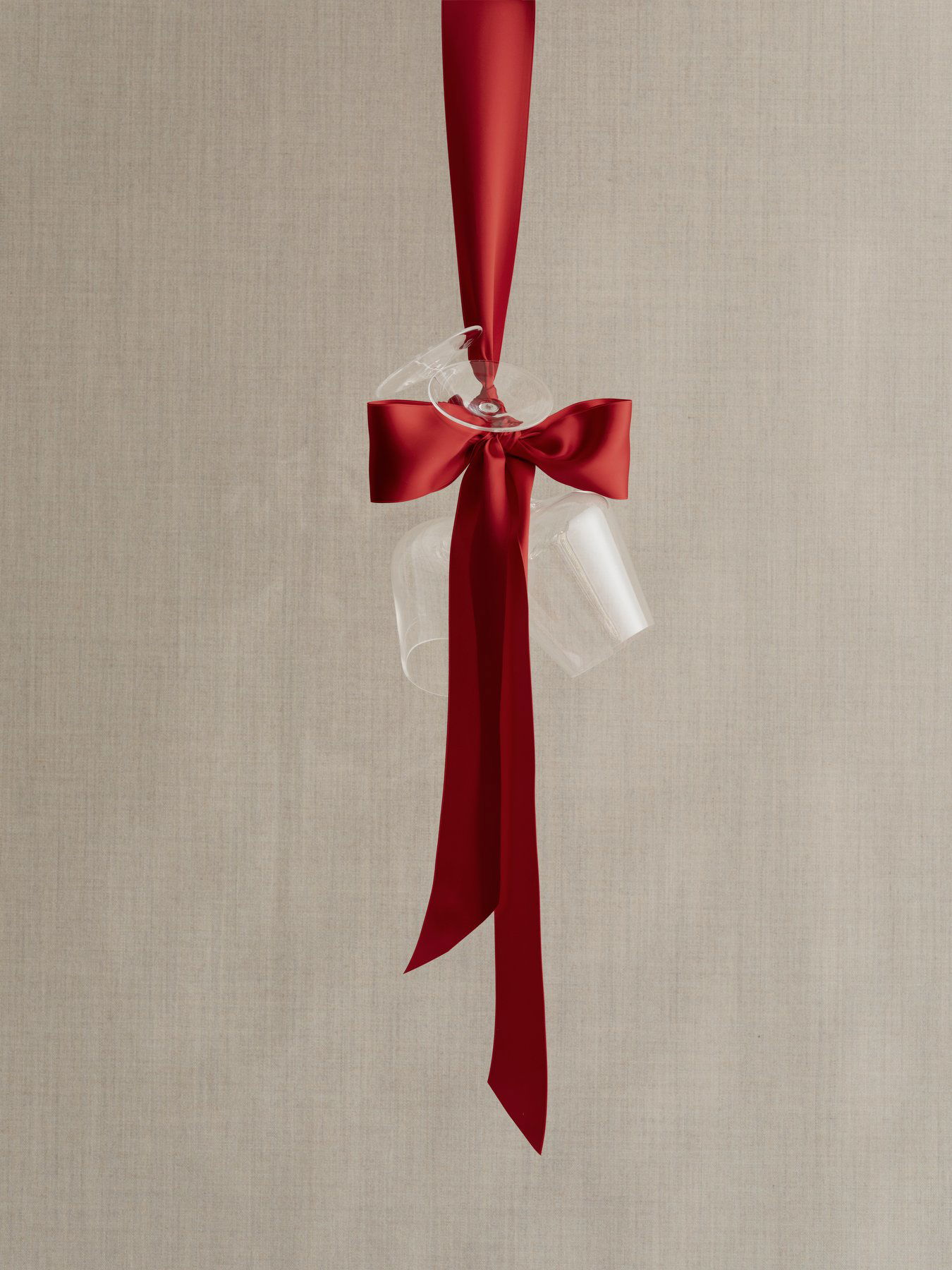 Elegantes Glasgeschirr, das mit einem roten Band vor einem neutralen Hintergrund schwebt.