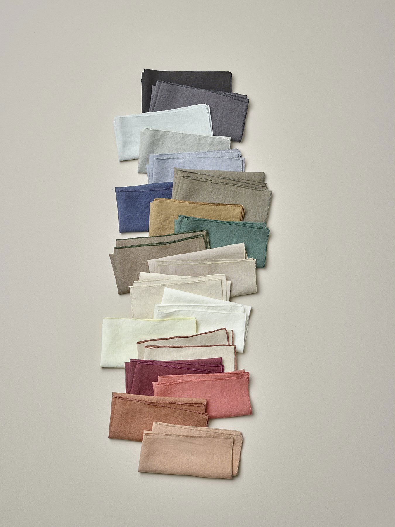 A vibrant display of neatly folded fabrics in various colors on a neutral background.