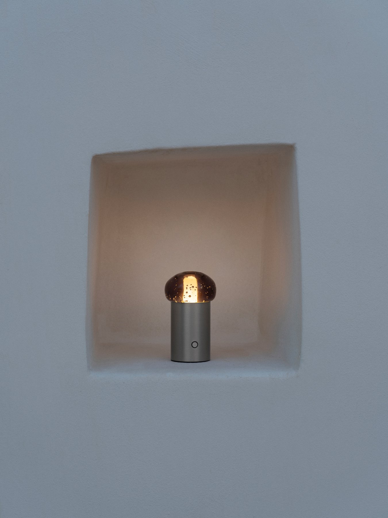 Moderne metallische Lampe, die eine ausgehöhlte Nische in einer weißen Wand beleuchtet.