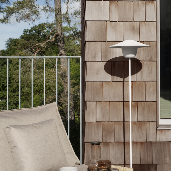 A modern outdoor lamp beside a cozy seating area on a wooden deck.