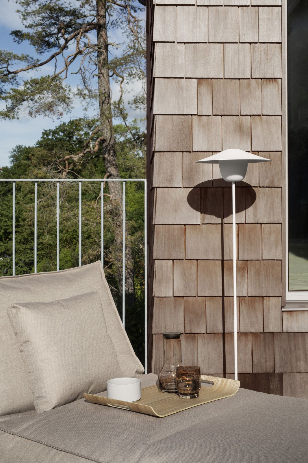 A modern outdoor lamp beside a cozy seating area on a wooden deck.