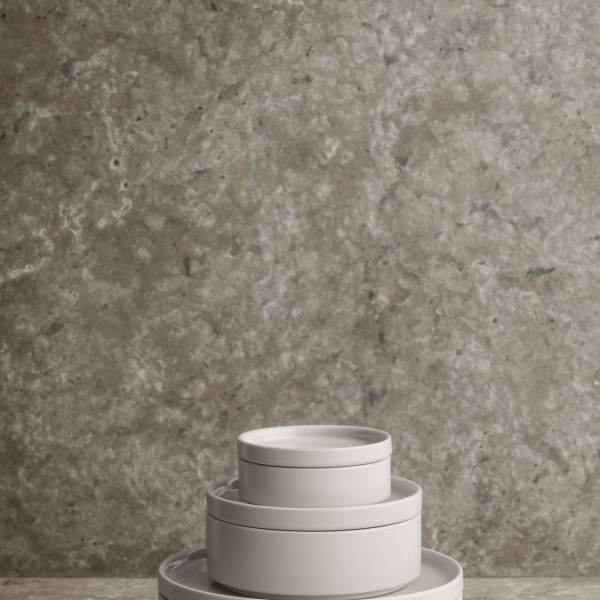 Minimalist white ceramic bowls stacked against a textured gray stone background.