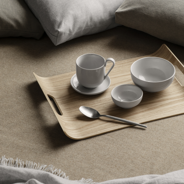 Elegant wooden tray with white dinnerware and a silver spoon on a cozy beige background.