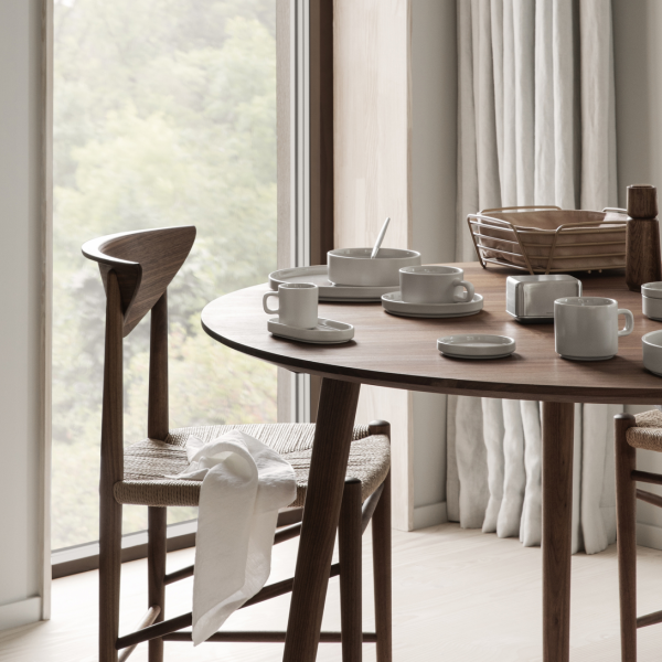 Modern dining table set with minimalist dishware and a scenic window view.