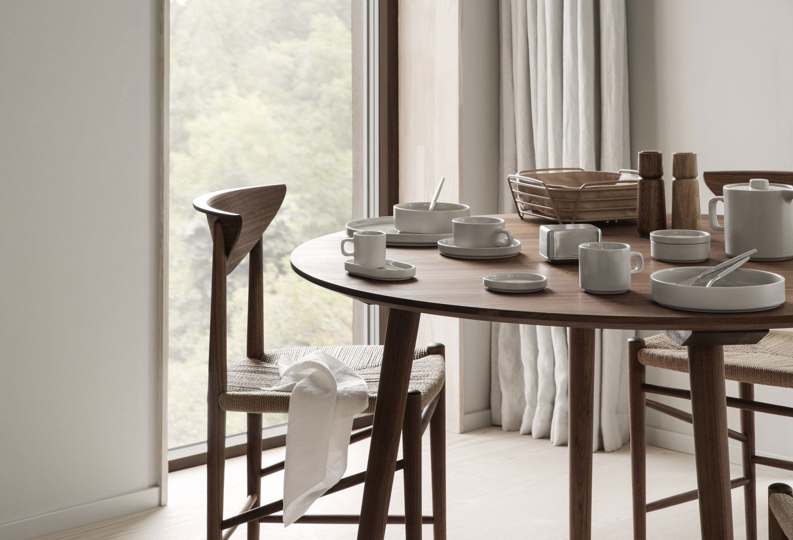 Modern dining table set with minimalist dishware and a scenic window view.