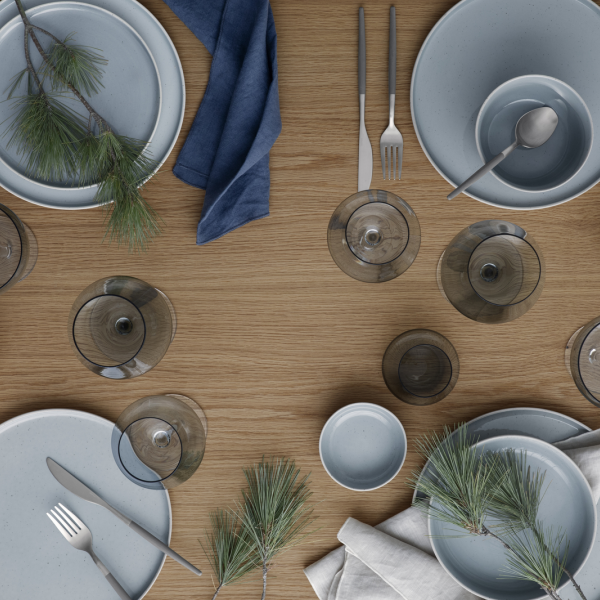 Elegant dining setup with blue tableware and pine accents on a wooden table.