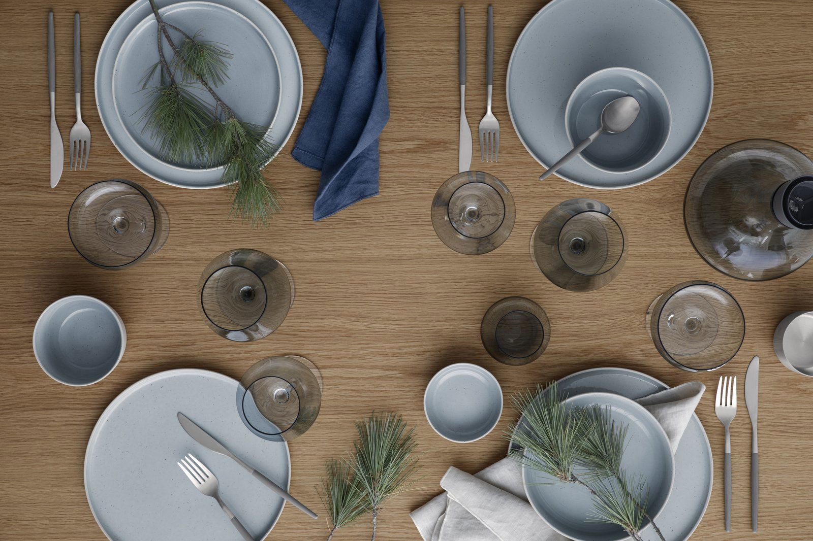 Elegant dining setup with blue tableware and pine accents on a wooden table.
