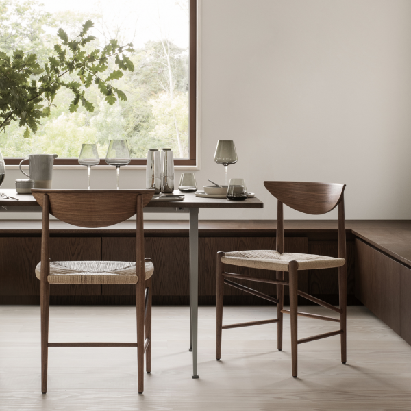 Modernes Esszimmer-Setup mit Holztischen und eleganten Gläsern in der Nähe eines großen Fensters.