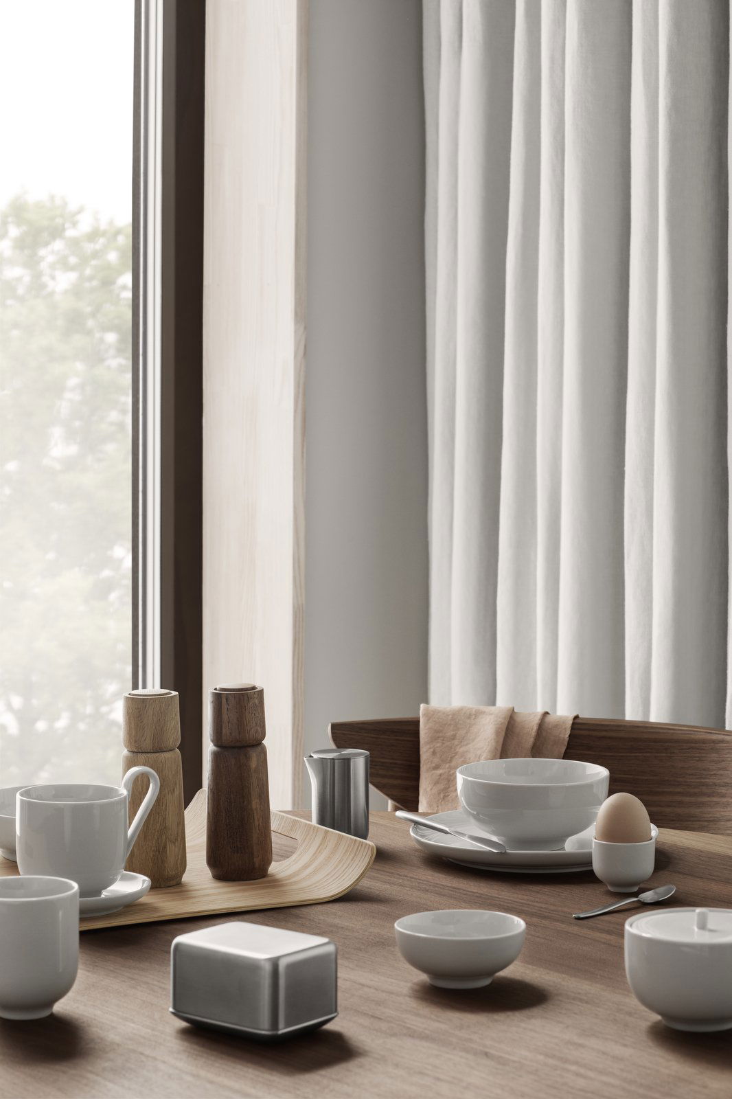 Elegant breakfast setting featuring minimalistic tableware by a window.