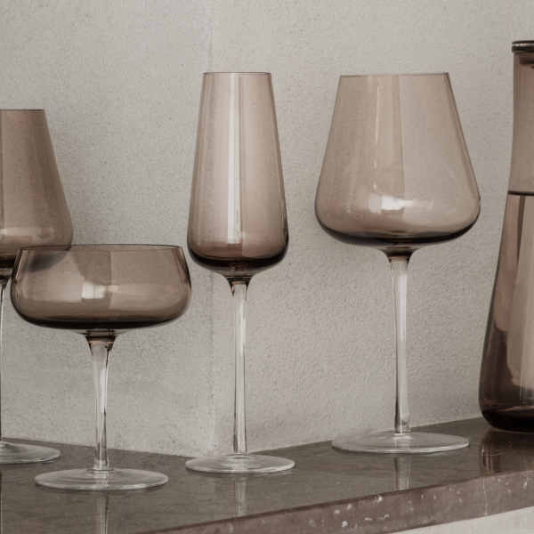 Elegant collection of smoky glassware displayed on a wooden shelf.