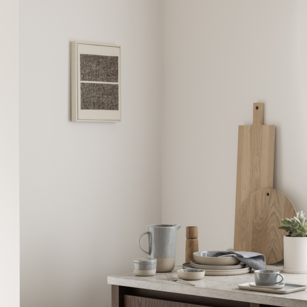 Minimalist dining setup with tableware, a pitcher, and modern wall art in a serene space.