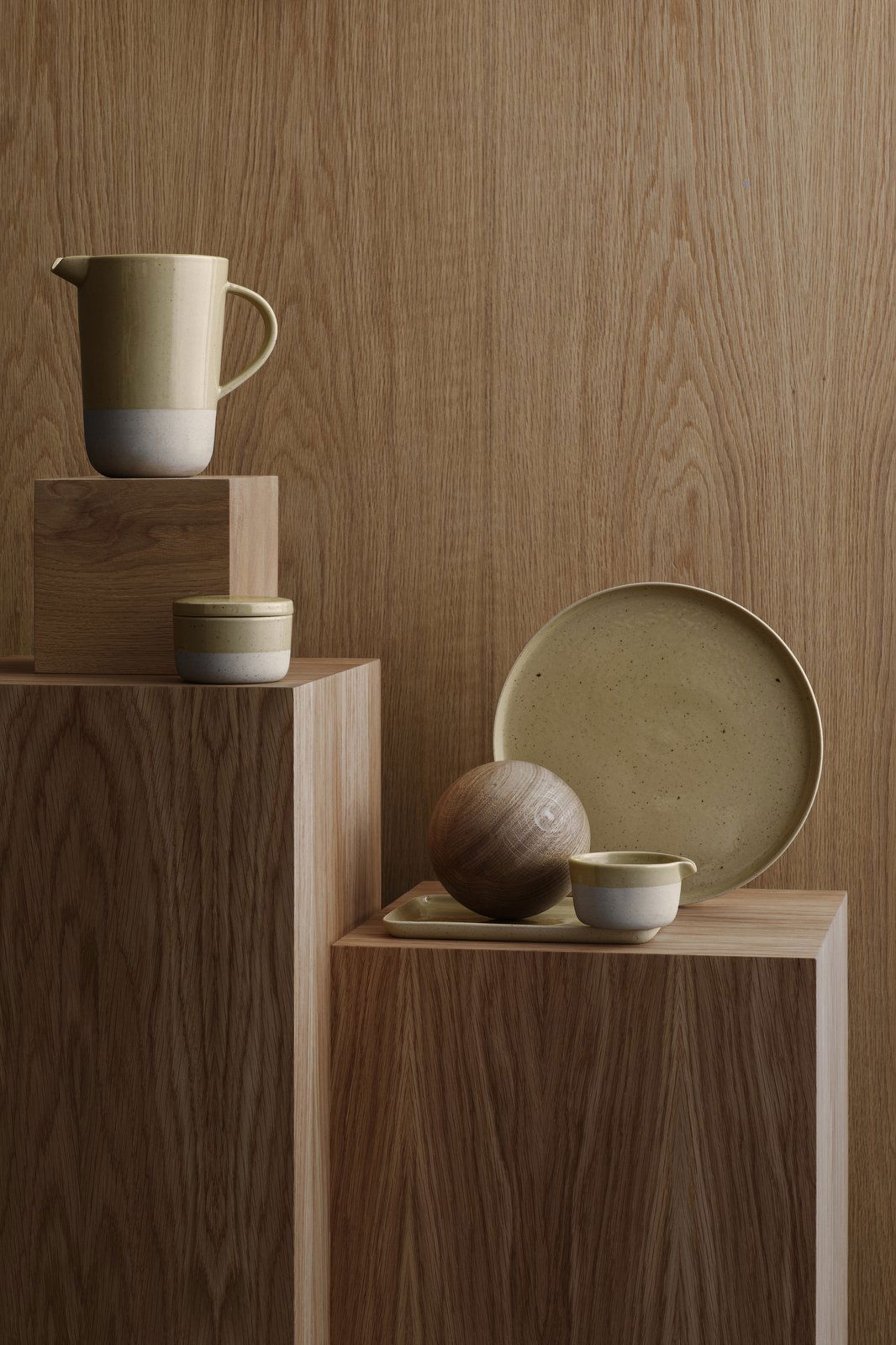 Minimalist ceramics and wooden objects displayed on wooden blocks for a stylish decor setting.