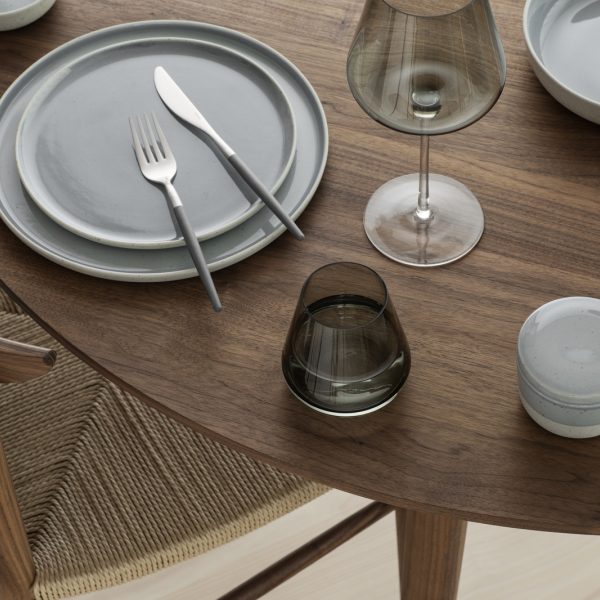 Elegant dining table setting with modern tableware and glassware on a wooden surface.