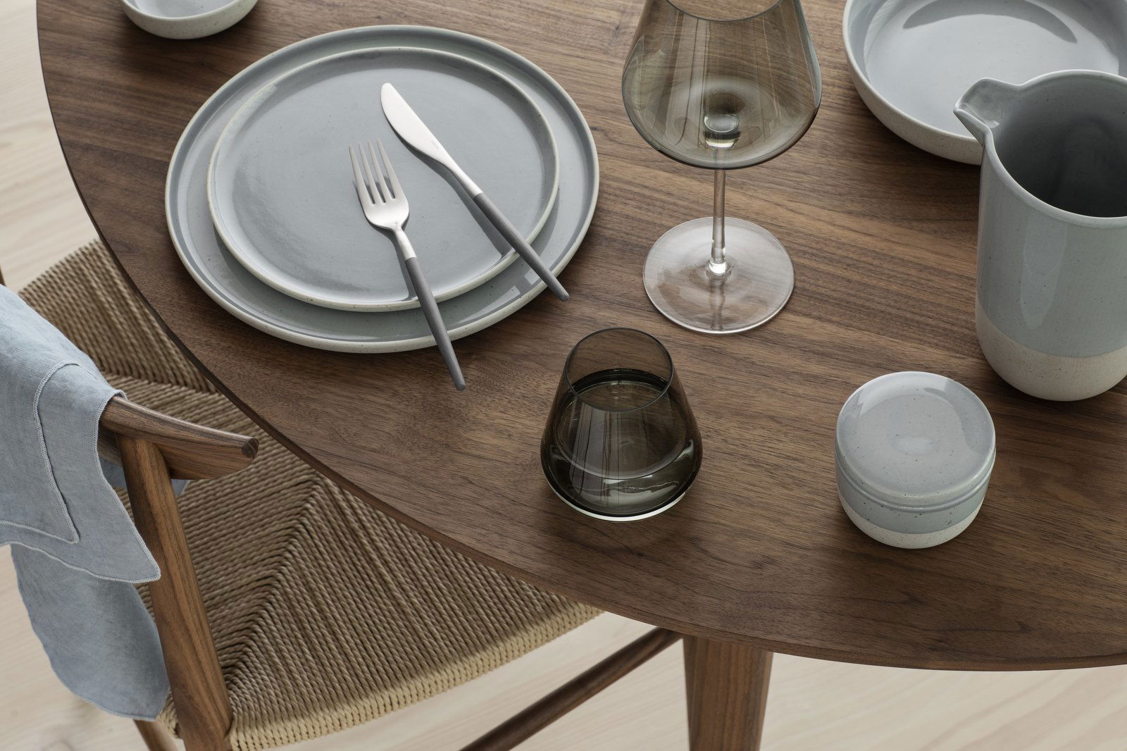Elegant dining table setting with modern tableware and glassware on a wooden surface.