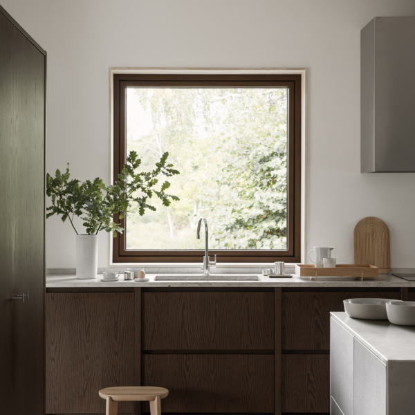 Moderne Küche mit Holzschränken, einem eleganten Spülbecken und einem großen Fenster, das ins Grüne blickt.