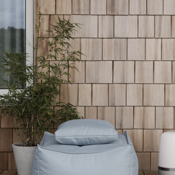 Cozy outdoor seating area with a bean bag, bamboo plant, and wooden wall backdrop.