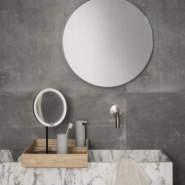 Modernes Badezimmer mit minimalistischer Dekoration, ausgestattet mit einem runden Spiegel und einer Marmorarbeitsplatte.