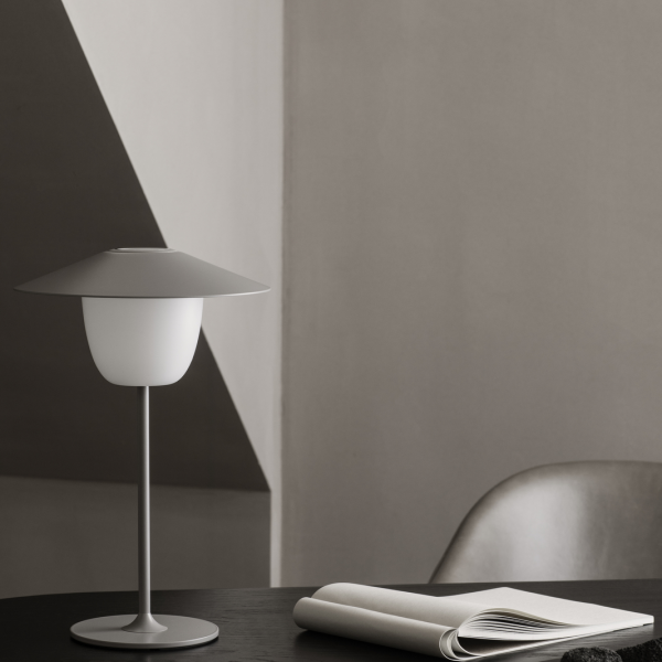 Moderne minimalistische Lampe auf einem eleganten Tisch mit sanfter Beleuchtung und Wänden in neutralen Farbtönen.