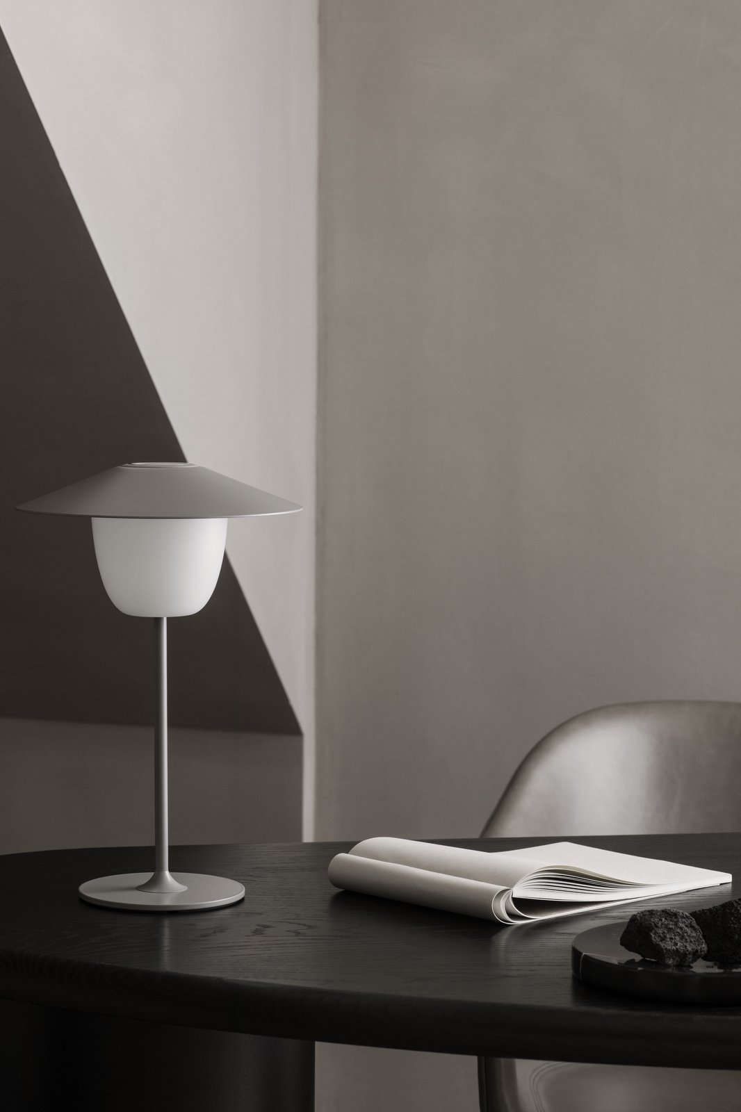 Moderne minimalistische Lampe auf einem eleganten Tisch mit sanfter Beleuchtung und Wänden in neutralen Farbtönen.