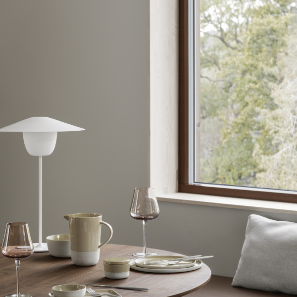 Elegantes Essgeschirr mit einer minimalistischen Lampe, Geschirr und einem Blick auf die Natur durch das Fenster.