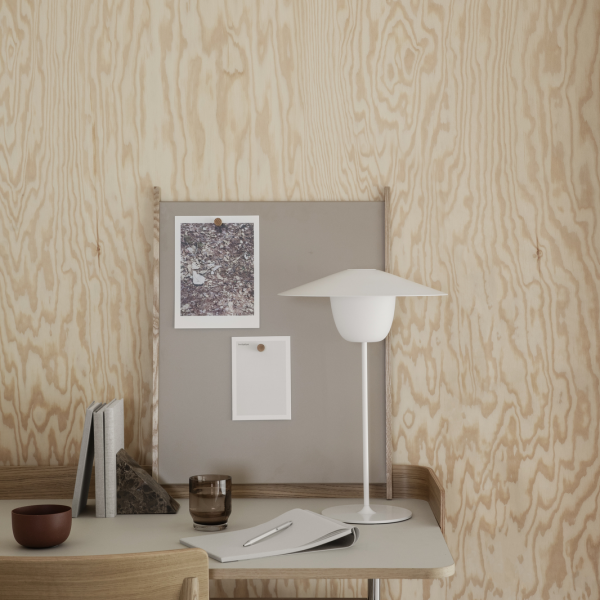 Modern workspace with minimalist decor, featuring a lamp, desk, and wall art in natural wood tones.