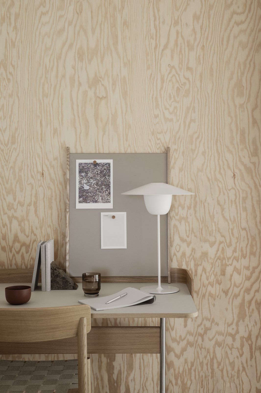 Modern workspace with minimalist decor, featuring a lamp, desk, and wall art in natural wood tones.